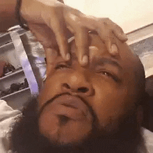 A Man With A Beard Is Holding His Hands To His Face . GIF