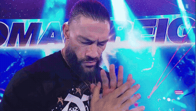 A Man With A Beard Is Holding His Hands Together In Front Of A Sign That Says Smart Fight . GIF