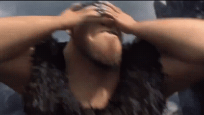 A Man With A Beard Is Holding His Head In Pain . GIF