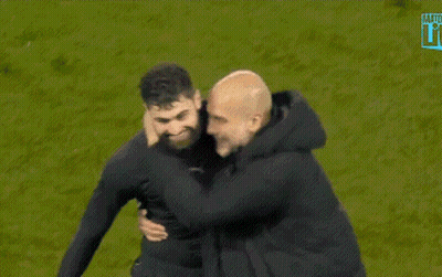 A Man With A Beard Is Hugging Another Man On A Field GIF