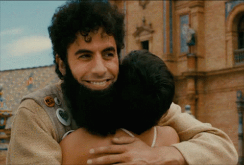 Man With Beard Hugging Another Man With N2 Badge GIF