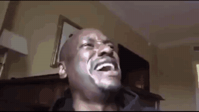 A Man With A Beard Is Laughing In A Room . GIF