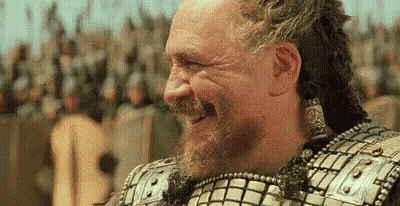 A Man With A Beard Is Laughing In Front Of A Crowd Of People In Armor . GIF
