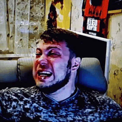 A Man With A Beard Is Laughing While Sitting In A Chair In Front Of A Television . GIF