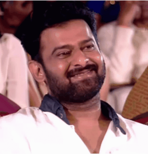 A Man With A Beard Is Laughing While Sitting In A Theatre . GIF