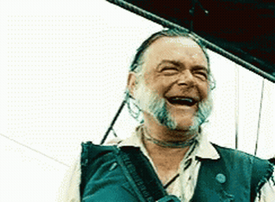 A Man With A Beard Is Laughing With His Mouth Wide Open GIF