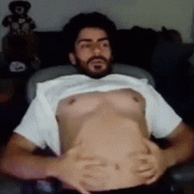 A Man With A Beard Is Laying Down With His Shirt Off GIF