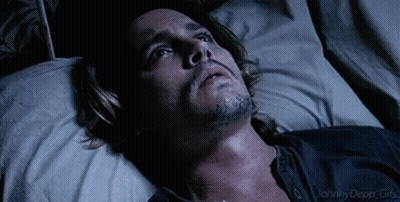 A Man With A Beard Is Laying In A Bed Looking Up At The Sky . GIF