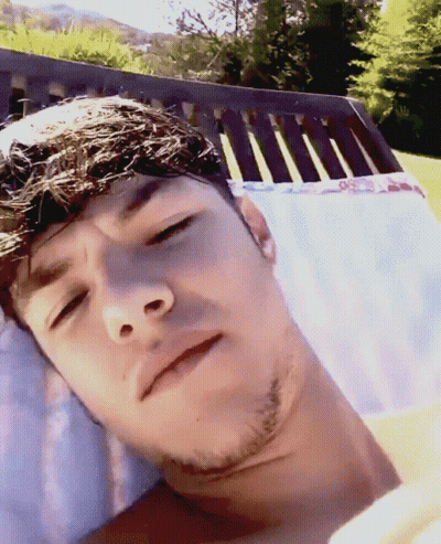 A Man With A Beard Is Laying In A Chair With His Eyes Closed GIF