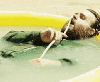 A Man With A Beard Is Laying In A Pool Drinking Water Through A Straw GIF