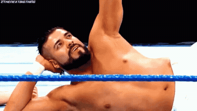 A Man With A Beard Is Laying In A Wrestling Ring With His Arm Up . GIF