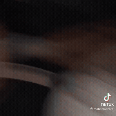 A Man With A Beard Is Laying On A Bed And Has A Tiktok On His Face . GIF