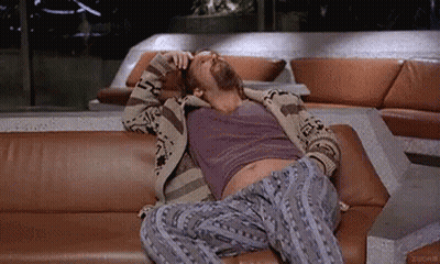 A Man With A Beard Is Laying On A Couch . GIF