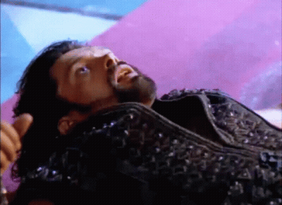 A Man With A Beard Is Laying On A Purple Blanket . GIF