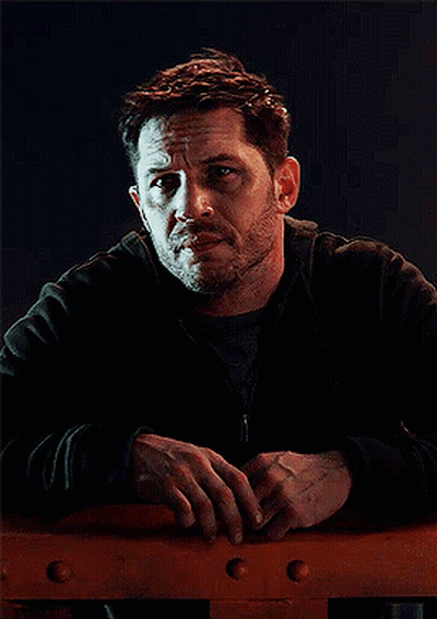 A Man With A Beard Is Leaning Against A Railing And Looking At The Camera GIF