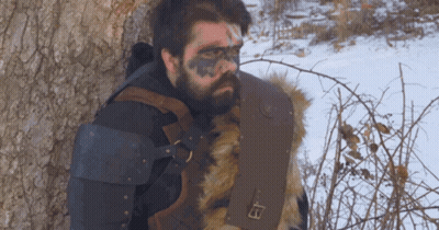 A Man With A Beard Is Leaning Against A Tree GIF