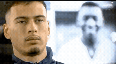 A Man With A Beard Is Looking At A Picture Of A Man With A Beard . GIF