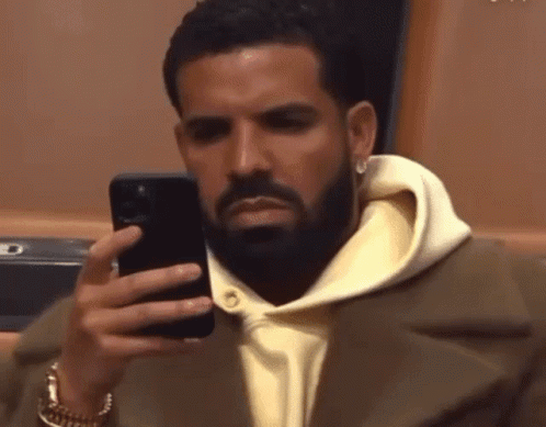 A Man With A Beard Is Looking At His Cell Phone GIF