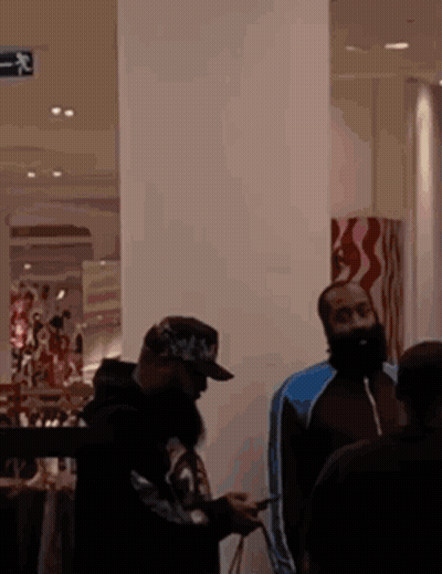 A Man With A Beard Is Looking At His Phone While Standing In A Store GIF