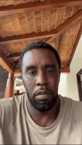 A Man With A Beard Is Looking At The Camera With A Wooden Ceiling In The Background GIF