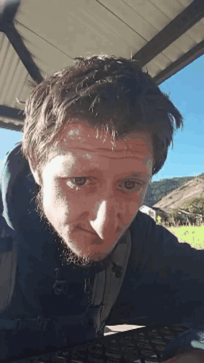 A Man With A Beard Is Looking At The Camera With His Eyes Closed GIF