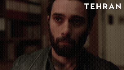 A Man With A Beard Is Looking At The Camera With Tehran Written In The Corner GIF