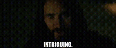 A Man With A Beard Is Looking At The Camera With The Words Intriguing . GIF