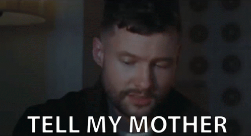 A Man With A Beard Is Looking At The Camera With The Words Tell My Mother Behind Him . GIF