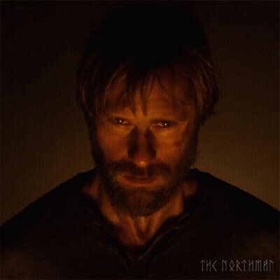 A Man With A Beard Is Looking At The Camera With The Words The Northman Behind Him GIF