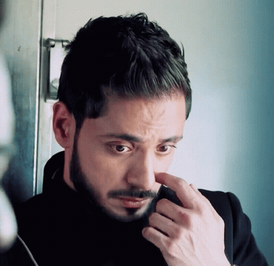 A Man With A Beard Is Looking Down At Something GIF