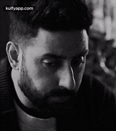 A Man With A Beard Is Looking Down In A Black And White Photo . GIF