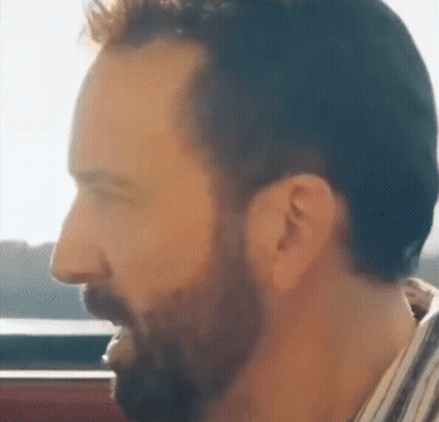 A Man With A Beard Is Looking Out A Window GIF