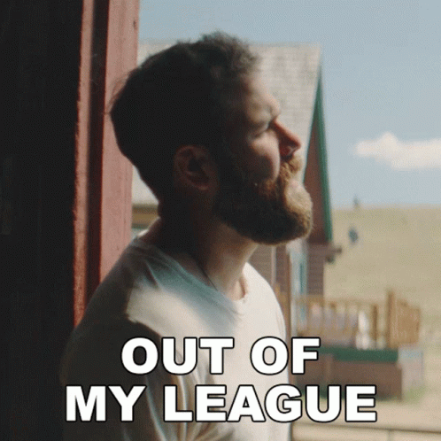 A Man With A Beard Is Looking Out Of A Window And The Words Out Of My League Are Above Him GIF