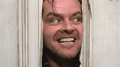 A Man With A Beard Is Looking Through A Door And Smiling . GIF