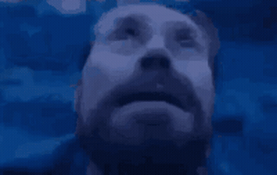 A Man With A Beard Is Looking Up At Something GIF