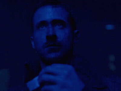 A Man With A Beard Is Looking Up In A Dark Blue Room GIF