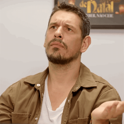A Man With A Beard Is Making A Face In Front Of A Sign That Says De Natal GIF