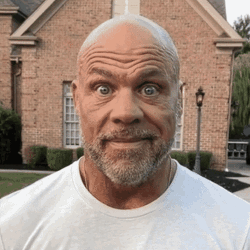 A Man With A Beard Is Making A Funny Face In Front Of A Brick House GIF