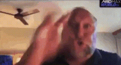 A Man With A Beard Is Making A Funny Face In Front Of A Ceiling Fan . GIF