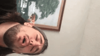 A Man With A Beard Is Making A Funny Face In Front Of A Painting . GIF