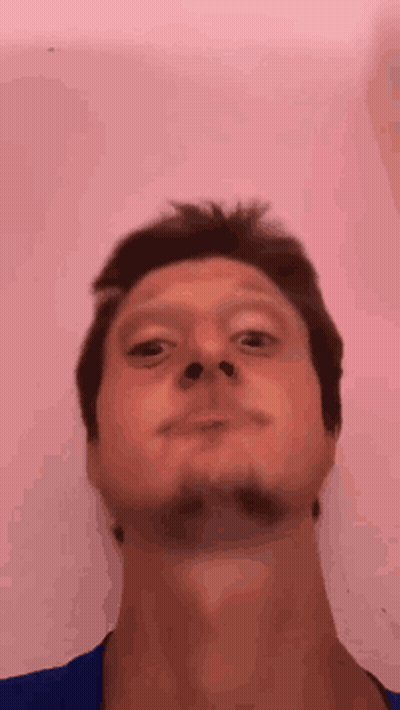 A Man With A Beard Is Making A Funny Face In Front Of A Pink Background . GIF