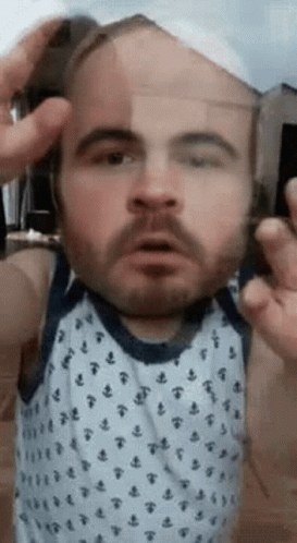 A Man With A Beard Is Making A Funny Face While Holding A Glass . GIF