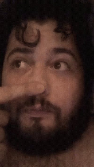 A Man With A Beard Is Making A Funny Face While Holding His Nose . GIF