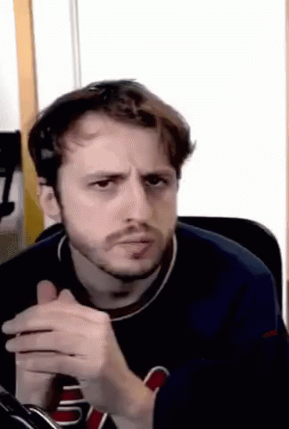 A Man With A Beard Is Making A Funny Face While Sitting In A Chair In Front Of A Window . GIF