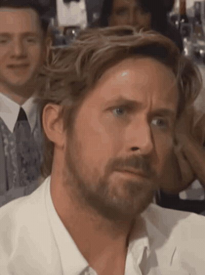 A Man With A Beard Is Making A Funny Face While Sitting In A Crowd . GIF