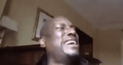 A Man With A Beard Is Making A Funny Face While Sitting In A Living Room . GIF