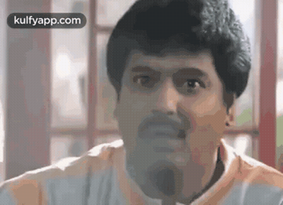 A Man With A Beard Is Making A Funny Face While Sitting In Front Of A Window . GIF