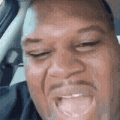 A Man With A Beard Is Making A Funny Face While Sitting In The Driver 'S Seat Of A Car . GIF