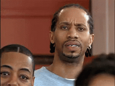 A Man With A Beard Is Making A Funny Face While Standing In A Crowd . GIF