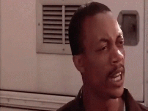 A Man With A Beard Is Making A Funny Face While Standing In Front Of A White Truck . GIF